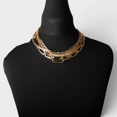 a black mannequin with a gold chain and red beads