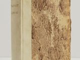 an old book sitting on top of a white table next to a white wall