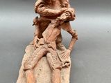 an old figurine of a man sitting on a rock