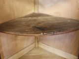 a corner shelf with a wooden top on a tile floor
