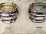 two silver cups sitting on a tray with spoons in them