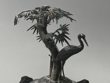 figurine plaquée argent représentant deux oiseaux et un arbre, posée sur un socle