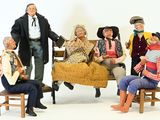 many figurines of people sitting on a bench together