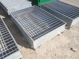 trois grilles métalliques posées par terre à côté d'un conteneur vert