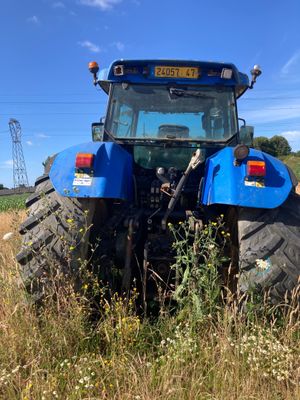 a blue tractor that is parked in a field
