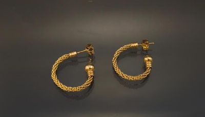 two pairs of gold hoop earrings on a black surface
