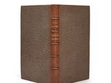 un vieux livre à la couverture brune posé sur une surface blanche