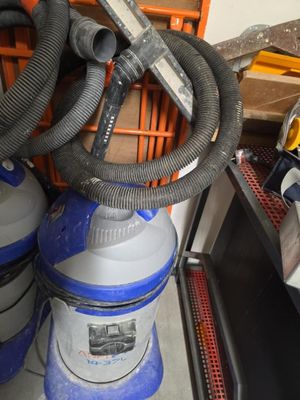 un aspirateur bleu et blanc posé à côté d'une pile d'autres aspirateurs