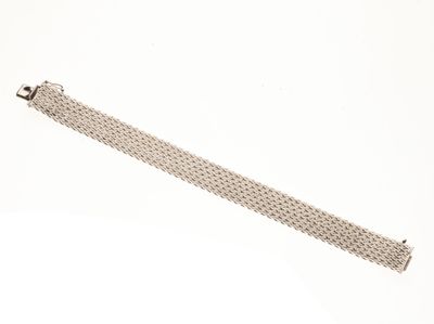 gros plan d'un bracelet métallique sur une surface blanche