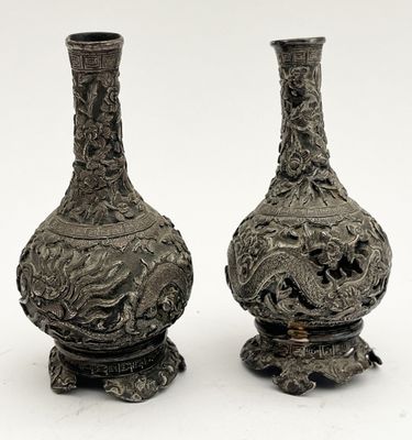deux vases en argent posés l'un à côté de l'autre sur une surface blanche