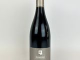 a bottle of red wine sitting on top of a white table