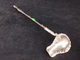 a glass shovel with a green handle sitting on a black surface