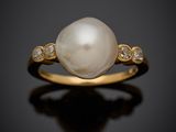 a white pearl and diamond ring on a black surface