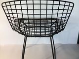 a black wire chair with a black seat and legs on a white surface
