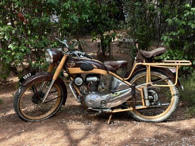 une moto garée sur la terre battue près de quelques arbres