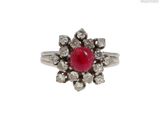 une image d'une bague avec une pierre rouge entourée de diamants blancs