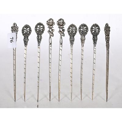 six silver spoons with ornate designs on them sitting on a white surface