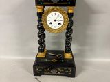 une horloge noire et or posée sur une surface blanche