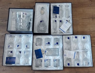 six vases en verre dans une boîte posée sur un plancher en bois