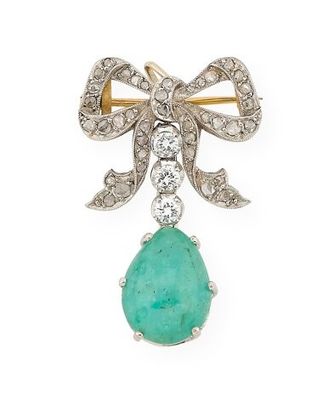 un gros plan sur une broche en forme d'arc, composée d'une pierre verte et de diamants