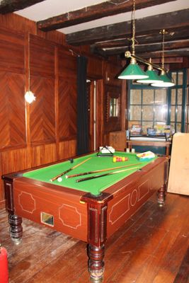 une table de billard au milieu d'une pièce, recouverte d'un tapis vert