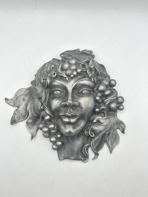 a metal sculpture of a woman with grapes on her head
