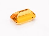 a close up of a yellow sapphire stone on a white surface