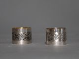two silver napkins with designs on them sitting on a table