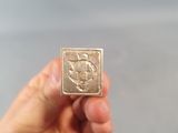 someone is holding a gold coin with a picture of a fish on it