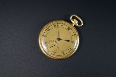 une montre de poche en or posée sur une surface noire