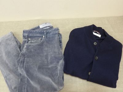 two pairs of jeans and a sweater sitting on the floor