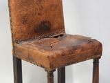 a wooden chair with a leather seat that has a chain on the back