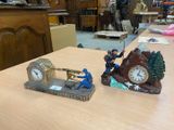 deux figurines posées sur une table sur laquelle se trouve une horloge