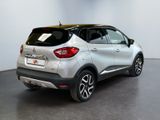 the rear end of a silver and black car in a room