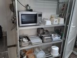 une cuisine équipée d'un micro-ondes et d'une étagère sur laquelle sont posés des plats