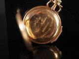 a close up of a gold pocket watch on a black surface