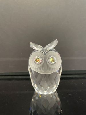 une figurine de chouette en verre posée sur une table