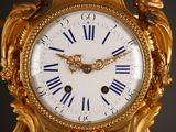 a gold clock with blue roman numerals on it