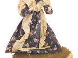 figurine représentant une femme en robe et chapeau, posée sur un coussin