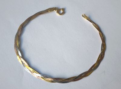 gros plan d'un bracelet en or sur une surface blanche