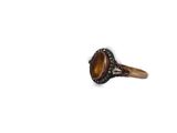 an image of a ring with a tiger eye stone surrounded by black diamonds