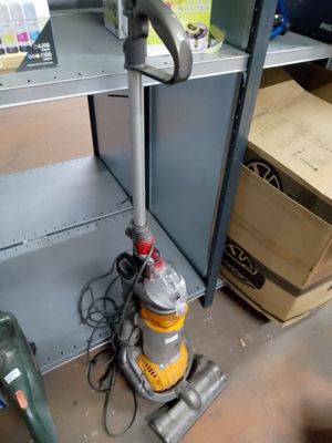 un aspirateur posé par terre à côté d'une étagère