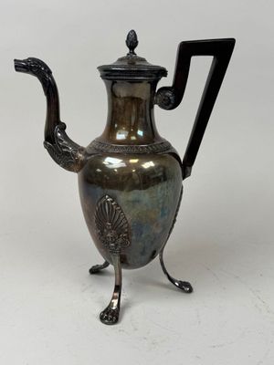 a silver tea pot with a handle on a stand