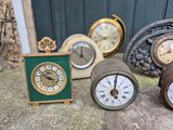 many different types of clocks sitting on the ground