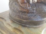 a statue of a person sitting on a rock with a bowl of soup