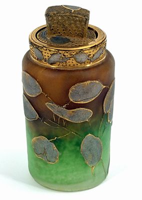 un vase vert et marron muni d'un couvercle, posé sur une surface blanche