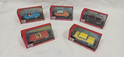 six petites voitures dans leurs boîtes, posées sur un lit recouvert d'un drap blanc