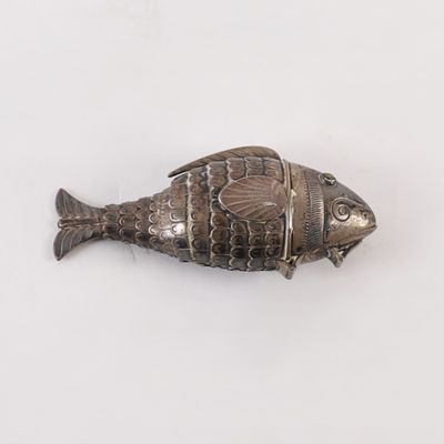 un objet argenté en forme de poisson posé sur une surface blanche