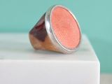 une image représentant une bague rose posée sur un bloc de marbre blanc