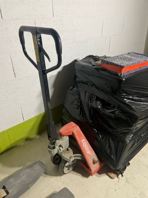 a pile of luggage and a hand truck in a room